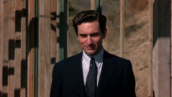 Movie still from “The Last Tycoon” (1976), directed by Elia Kazan – A man wearing a suit and tie standing in front of a building; Close Up shot, Low angle