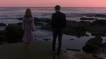 Movie still from “The Last Tycoon” (1976), directed by Elia Kazan – A man and a woman walking on the beach at sunset; Wide shot, Over the shoulder angle