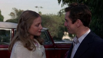 Movie still from “The Last Tycoon” (1976), directed by Elia Kazan – A man and a woman standing next to each other in front of a red truck; Close Up shot, Over the shoulder angle