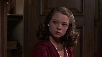 Movie still from “The Last Tycoon” (1976), directed by Elia Kazan – A young woman with long hair and a pearl necklace; Close Up shot, Over the shoulder angle