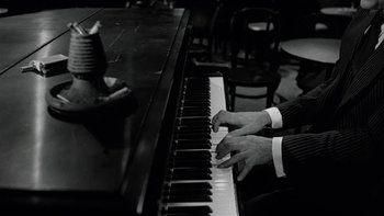 Movie still from “The Last Tycoon” (1976), directed by Elia Kazan – A person playing a piano in a black and white photo; Close Up shot, High angle