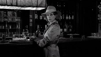 Movie still from “The Last Tycoon” (1976), directed by Elia Kazan – A black and white photo of a woman wearing a hat; Medium shot, Over the shoulder angle