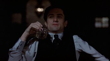 Movie still from “The Last Tycoon” (1976), directed by Elia Kazan – A man in a vest and tie holding a glass of beer; Close Up shot, Low angle