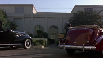 Movie still from “The Last Tycoon” (1976), directed by Elia Kazan – A couple of cars parked in front of a building; Extreme Wide shot, Low angle