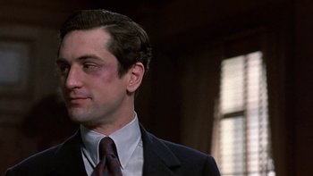 Movie still from “The Last Tycoon” (1976), directed by Elia Kazan – A person wearing a suit and tie; Close Up shot, Over the shoulder angle