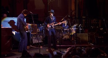 Movie still from “The Last Waltz” (1978), directed by Martin Scorsese – A group of people on a stage playing guitar; Wide shot, Low angle