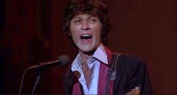 Movie still from “The Last Waltz” (1978), directed by Martin Scorsese – A man in a suit and tie singing into a microphone; Close Up shot, Low angle