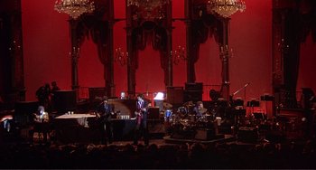 Movie still from “The Last Waltz” (1978), directed by Martin Scorsese – A group of people on a stage playing instruments; Extreme Wide shot, High angle
