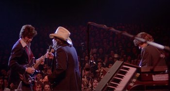 Movie still from “The Last Waltz” (1978), directed by Martin Scorsese – A man with a hat and a microphone in front of an audience; Wide shot, High angle