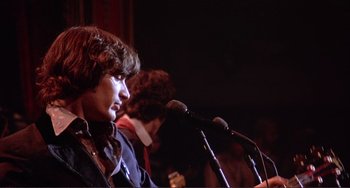 Movie still from “The Last Waltz” (1978), directed by Martin Scorsese – A man is speaking into a microphone on a stage; Close Up shot, Low angle