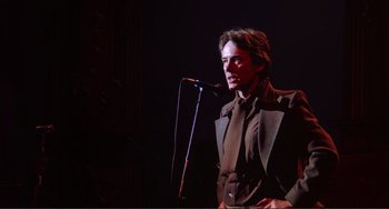 Movie still from “The Last Waltz” (1978), directed by Martin Scorsese – A man standing in front of a microphone on a stage; Medium shot, Low angle