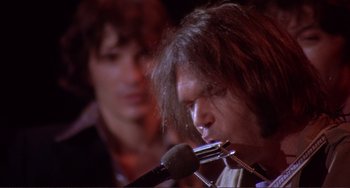 Movie still from “The Last Waltz” (1978), directed by Martin Scorsese – A man with long hair is holding a microphone; Extreme Close Up shot, Low angle