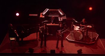 Movie still from “The Last Waltz” (1978), directed by Martin Scorsese – Two men are performing on a stage in front of an organ; Extreme Wide shot, High angle