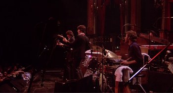 Movie still from “The Last Waltz” (1978), directed by Martin Scorsese – A group of people playing instruments on a stage; Extreme Wide shot, Low angle