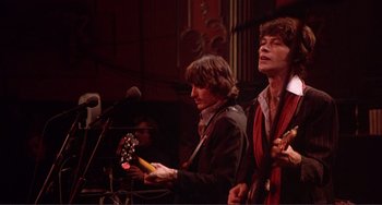 Movie still from “The Last Waltz” (1978), directed by Martin Scorsese – A group of people that are standing in a room together; Medium shot, Low angle