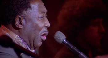 Movie still from “The Last Waltz” (1978), directed by Martin Scorsese – A person with a microphone; Close Up shot, High angle