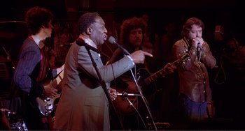 Movie still from “The Last Waltz” (1978), directed by Martin Scorsese – A group of people that are singing together; Medium shot, Low angle