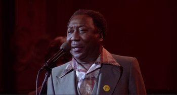 Movie still from “The Last Waltz” (1978), directed by Martin Scorsese – A man in a suit and tie holding a microphone; Close Up shot, Low angle