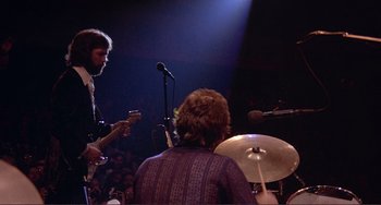 Movie still from “The Last Waltz” (1978), directed by Martin Scorsese – A band playing on a stage in front of an audience; Medium shot, Low angle