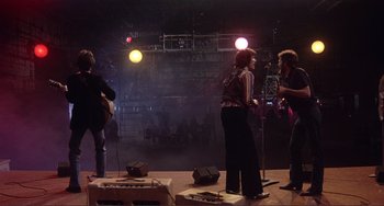 Movie still from “The Last Waltz” (1978), directed by Martin Scorsese – A group of people standing on a stage with microphones; Wide shot, Low angle