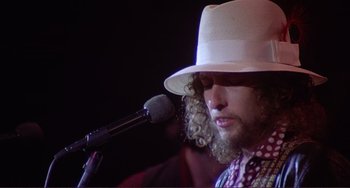 Movie still from “The Last Waltz” (1978), directed by Martin Scorsese – A man in a white hat is singing into a microphone; Close Up shot, Low angle