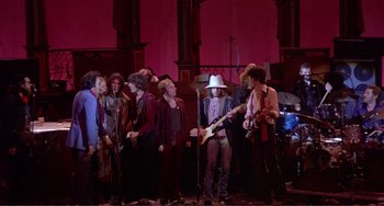 Movie still from “The Last Waltz” (1978), directed by Martin Scorsese – A group of people standing next to each other on a stage; Wide shot, High angle