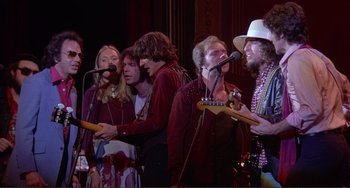 Movie still from “The Last Waltz” (1978), directed by Martin Scorsese – A group of people standing next to each other holding guitars; Medium shot, Low angle