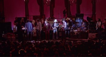 Movie still from “The Last Waltz” (1978), directed by Martin Scorsese – A group of people standing on a stage with instruments; Wide shot, High angle