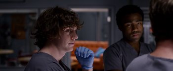 Movie still from “The Lazarus Effect” (2015), directed by David Gelb – A young man wearing blue gloves and a black shirt; Close Up shot, Over the shoulder angle