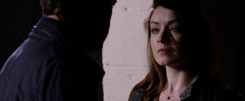 Movie still from “The Lazarus Effect” (2015), directed by David Gelb – A young woman is standing in front of a brick wall; Close Up shot, Over the shoulder angle