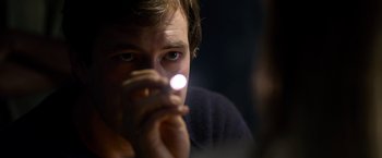 Movie still from “The Lazarus Effect” (2015), directed by David Gelb – A young man holding a flashlight in front of his face; Close Up shot, Over the shoulder angle