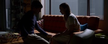 Movie still from “The Lazarus Effect” (2015), directed by David Gelb – A man and a woman sitting on top of an orange couch; Medium shot, Over the shoulder angle