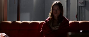Movie still from “The Lazarus Effect” (2015), directed by David Gelb – A woman wrapped in a blanket sitting on a red couch; Medium shot, Low angle