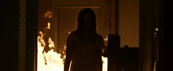 Movie still from “The Lazarus Effect” (2015), directed by David Gelb – A woman standing in front of a fire in a room; Medium shot, Over the shoulder angle