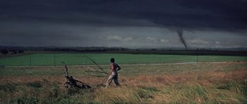 Movie still from “The Learning Tree” (1969), directed by Gordon Parks – A man walking through a field with a tree in the background; Extreme Wide shot, Low angle