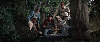 Movie still from “The Learning Tree” (1969), directed by Gordon Parks – A group of men sitting next to each other in the woods; Medium shot, High angle