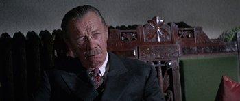 Movie still from “The Learning Tree” (1969), directed by Gordon Parks – An older man wearing a suit and tie sitting in a chair; Close Up shot, Low angle