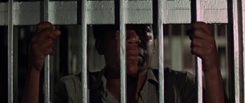 Movie still from “The Learning Tree” (1969), directed by Gordon Parks – A man in a jail cell looking through the bars; Close Up shot, Low angle