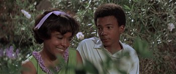 Movie still from “The Learning Tree” (1969), directed by Gordon Parks – A man and a woman sitting next to each other in front of trees; Close Up shot, Low angle