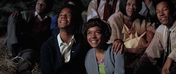 Movie still from “The Learning Tree” (1969), directed by Gordon Parks – A couple of people that are sitting next to each other; Medium shot, Low angle
