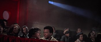 Movie still from “The Learning Tree” (1969), directed by Gordon Parks – Two young boys are sitting in front of a red curtain; Medium shot, Low angle