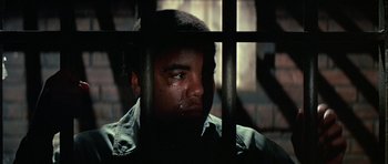 Movie still from “The Learning Tree” (1969), directed by Gordon Parks – A man in a jail cell with his eyes closed; Close Up shot, Low angle