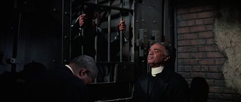 Movie still from “The Learning Tree” (1969), directed by Gordon Parks – A man in a black robe and a man in a white shirt and a man in a black robe and a man in a white shirt and a; Medium shot, High angle