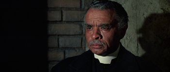 Movie still from “The Learning Tree” (1969), directed by Gordon Parks – An older man wearing a priest's outfit; Close Up shot, Low angle