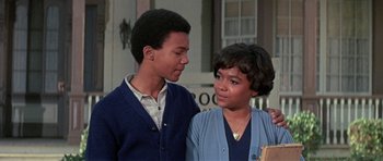 Movie still from “The Learning Tree” (1969), directed by Gordon Parks – A young man standing next to an older woman in front of a building; Close Up shot, Low angle