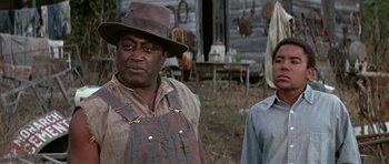 Movie still from “The Learning Tree” (1969), directed by Gordon Parks – A man and a woman standing next to each other in a field; Medium shot, Low angle