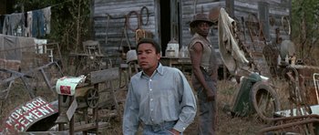 Movie still from “The Learning Tree” (1969), directed by Gordon Parks – A man standing next to another man in front of an old barn; Medium shot, Low angle