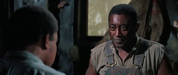 Movie still from “The Learning Tree” (1969), directed by Gordon Parks – A man in a brown shirt is talking to another man; Close Up shot, Over the shoulder angle