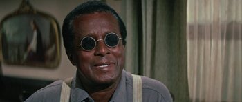Movie still from “The Learning Tree” (1969), directed by Gordon Parks – A person wearing round sunglasses; Close Up shot, Low angle