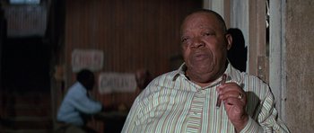 Movie still from “The Learning Tree” (1969), directed by Gordon Parks – An older man wearing a striped shirt is looking at the camera; Close Up shot, Low angle